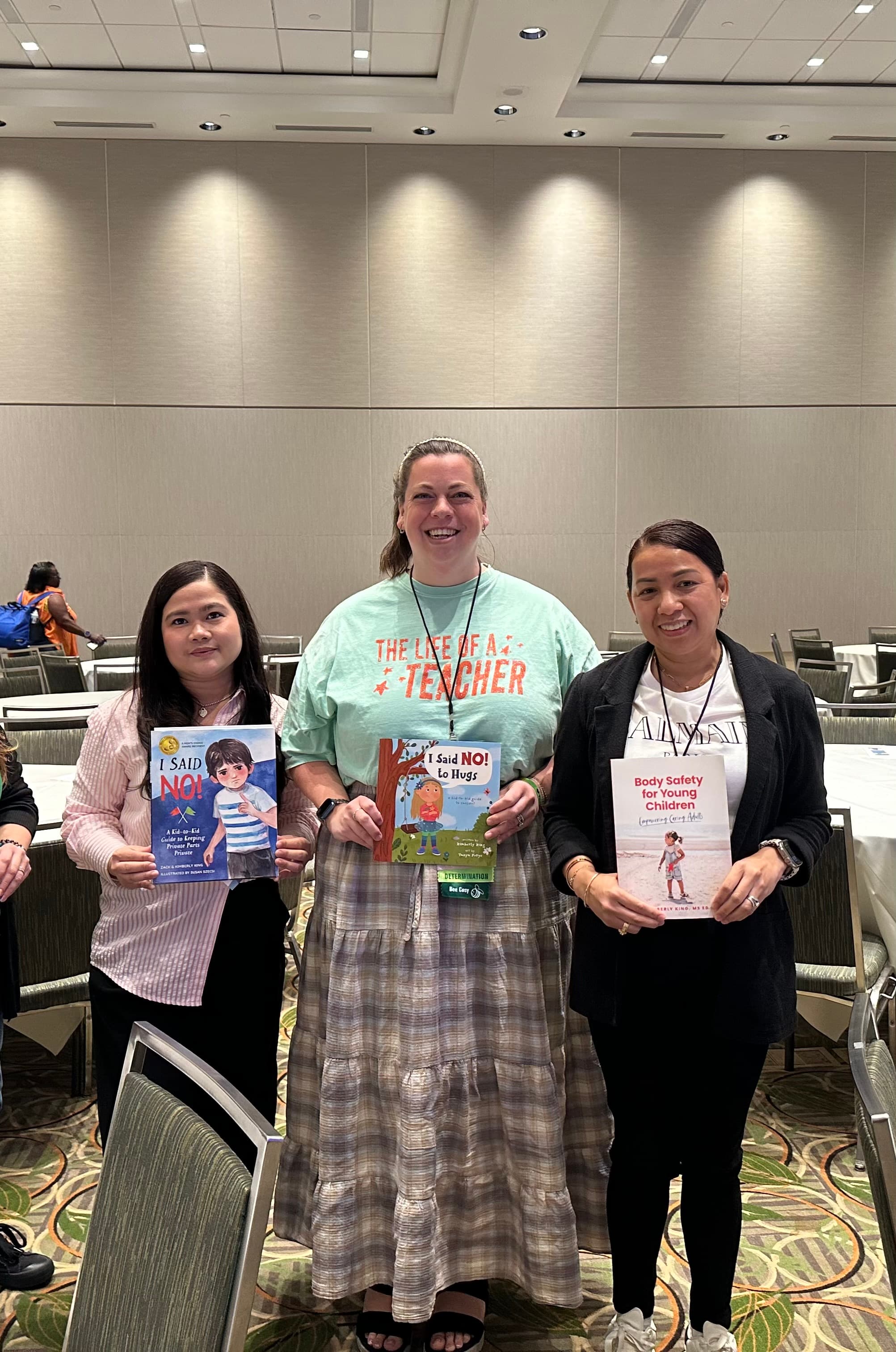 Three teachers holding Kimberly King's body safety books at a staff training workshop